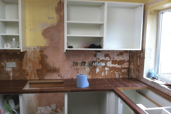 image shows a kitchens in the middle of refurbishment with missing tiles and cupboard doors