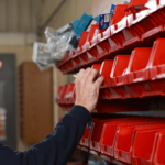 a person is standing in front of a shelf with red containers