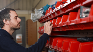 a person is standing in front of a shelf with red containers