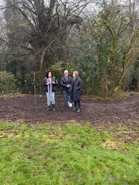 3 people stood planting a tree