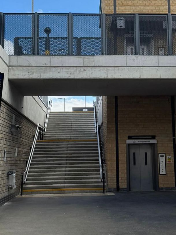Area at Mirfield Station featuring a wide staircase with handrails and a passenger lift providing step free access between platform levels. The modern station infrastructure includes concrete walkways, brick walls, safety barriers, and improved accessibility features installed by DASCO Construction.